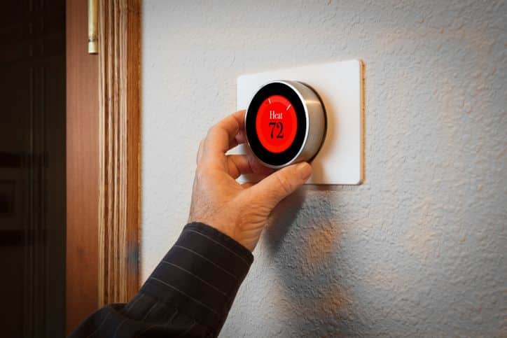 hand adjusting a digital thermostat