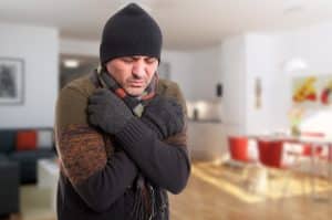 man shivering inside of cold house